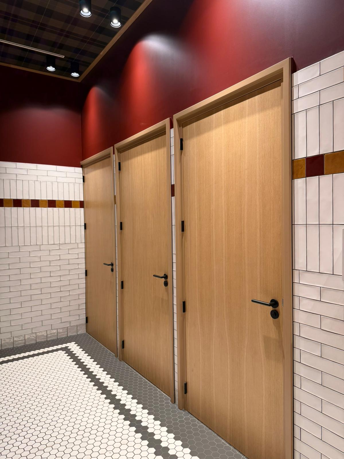 Toiletruimte met eiken deuren, witte tegels en bordeauxrode wand